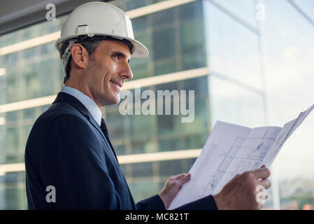 Man wearing hard hat reviewing blueprint Stock Photo