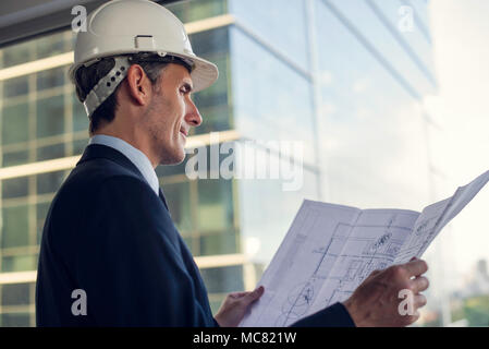 Man wearing hard hat reviewing blueprint Stock Photo