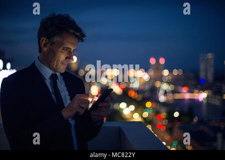 Businessman on high rise rooftop using mobile phone Stock Photo