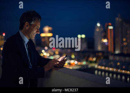 Businessman on high rise rooftop using mobile phone Stock Photo