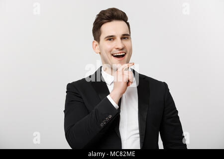 Business Concept: Smiling thoughtful handsome man standing on white isolated background and touching his chin with hand Stock Photo
