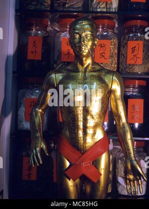 Chinese bronze figure marked with the secret lines of force which are used in acupuncture. Photographed in the surgery of a Chinese acupuncturist, Shatin. Stock Photo