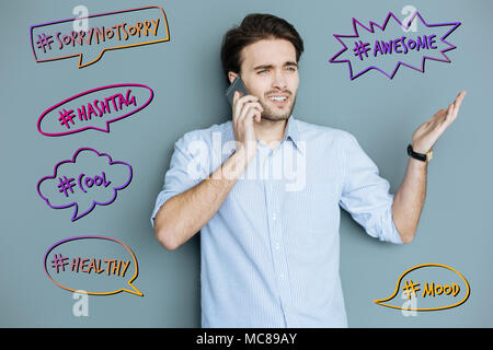Emotional blogger frowning while talking on the phone Stock Photo