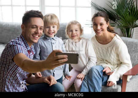 Happy family with adopted kids taking selfie together, smiling couple with son and daughter posing for self portrait, young father making photo or sho Stock Photo