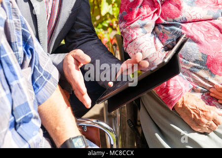 old womans is having wearable device smart watch in care home retirement house. Doctor explaining technologies Stock Photo