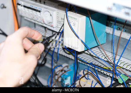 engineer hands installing electrical components in fuse box. Industry 4. Measuring voltage Stock Photo