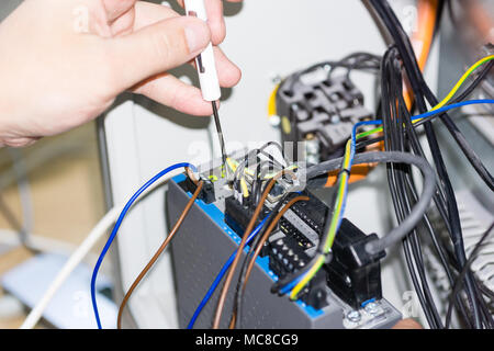 engineer hands installing electrical components in fuse box. Industry 4. Measuring voltage Stock Photo