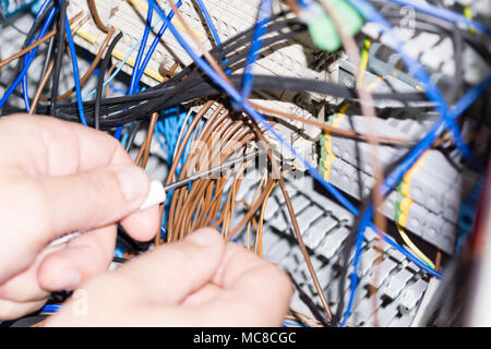 engineer hands installing electrical components in fuse box. Industry 4. Measuring voltage Stock Photo