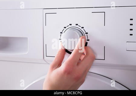 Close-up Of A Person's Hand Turning Button Of Washing Machine Stock Photo