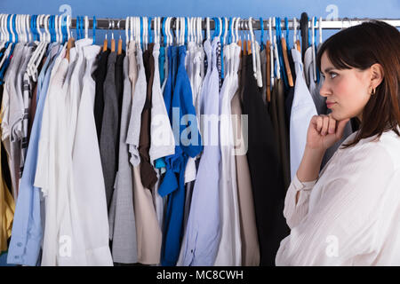 Side View Of A Young Woman Looking At Clothes On Clothes Rail In Store Stock Photo