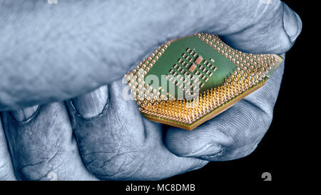 Mysterious hand destroys computer chip with critical flaw. Close-up of broken processor in expert's fingers on black background. Spying, hacking idea. Stock Photo