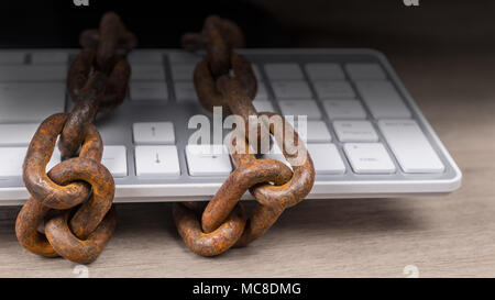 Rusty chains on computer keyboard in close-up on dark background. Concept of internet censorship, spy, digitization, cyber security, PII, SPI, GDPR. Stock Photo