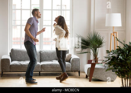 Young romantic carefree couple in love dancing spending time together at home, cheerful smiling man and woman having fun in cozy modern living room, h Stock Photo