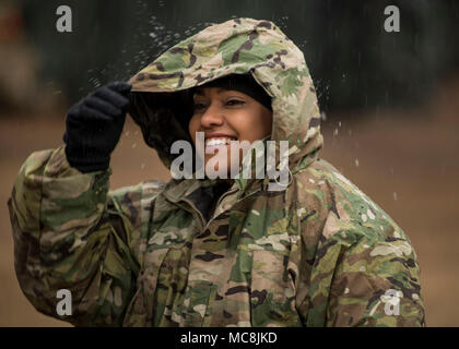 Pfc. Ana Mata, a U.S. Army Reserve automated logistics specialist, with the 812th Quartermaster Company, out of Kingsville, Texas, stands in the rain waiting for chow during Operation Cold Steel at Fort McCoy, Wisconsin, March 26, 2018.  This iteration of Cold Steel is called Task Force Triad, a mounted gunnery training exercise in which Soldiers work as truck teams to quailfy on live-fire driving lanes. Task Force Triad runs from February to May. Each team who trains here completes a 14-day cycle that includes primary marksmanship training, a gunner skill test, digital simulated gunnery, grou Stock Photo
