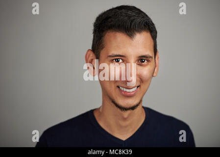 Portrait of young smiling arab man on grey background Stock Photo