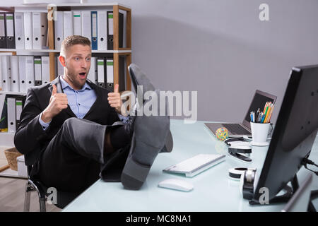 Young Businessman Looking At Computer Gesturing Thumbs Up Stock Photo