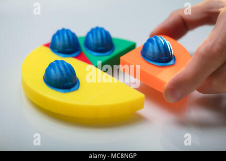 Human Hand Placing Last Orange Piece Into Pie Chart With Blue Hard Hat Stock Photo