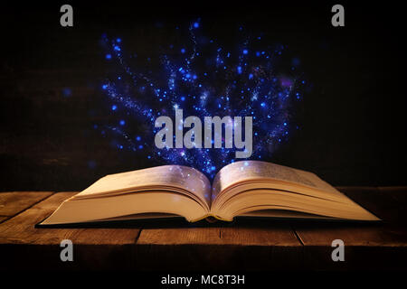 image of open antique book on wooden table with glitter overlay Stock Photo