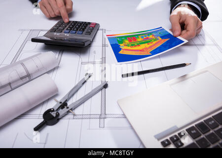 Close-up Of Architecture's Hand Using Calculator While Holding Home Thermal Heat Loss Stock Photo