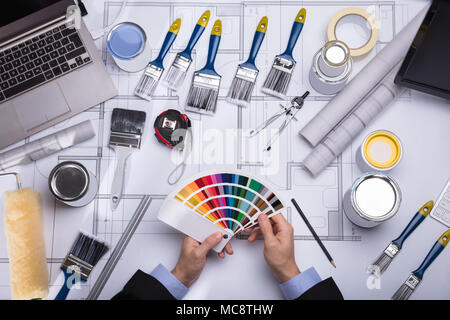 Elevated View Of An Architect's Hand Holding Color Guide Swatch On Blueprint Stock Photo