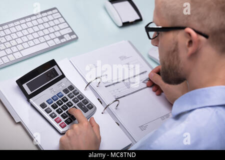 Businessman Using Calculator For Calculating Invoice At Desk Stock Photo