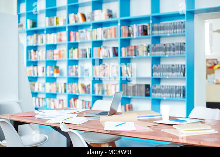 Long table with copybooks, books and laptop in the middle of college library during lesson Stock Photo