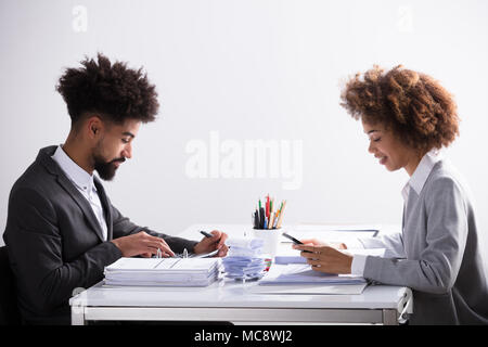 Side View Of Two Young Businesspeople Analyzing Bill In Office Stock Photo