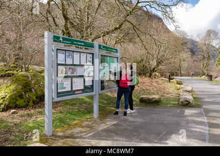 Two girls with backpacks looking at the Information board with map of walking trials in Glendalough at the Wicklow Mountains National Park in Ireland