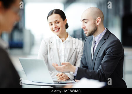 One of managers explaining his colleague online information while analyzing statistics of stock market sales Stock Photo