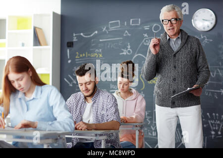Mature confident professor reading lecture to his students at lesson in college or university Stock Photo