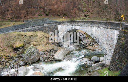 old stone bridge crossing a wild river with trail markers and hiking trails on both sides Stock Photo