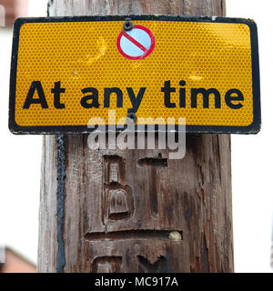 No Parking at any time sign with red circle with white fill symbol on a yellow-orange background on wooden telegraph pole Stock Photo