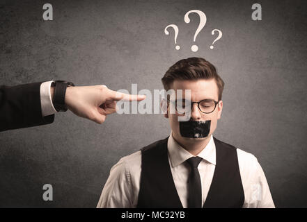 Caucasian business hand pointing at scared employee with big white question marks above his head Stock Photo