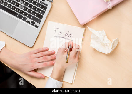 businesswoman making notes in a notebook, top view on the desktop, in the frame of the hand Stock Photo