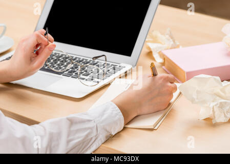 close-up of female hands record information in a notebook and keep glasses Stock Photo