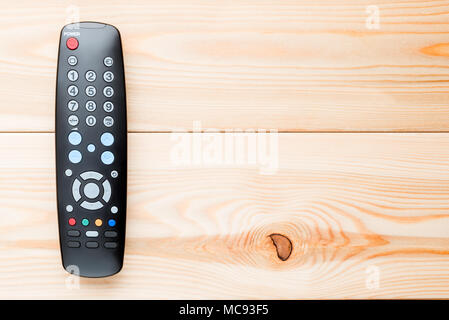 remote control for switching channels on the TV set on the wooden floor on the right Stock Photo