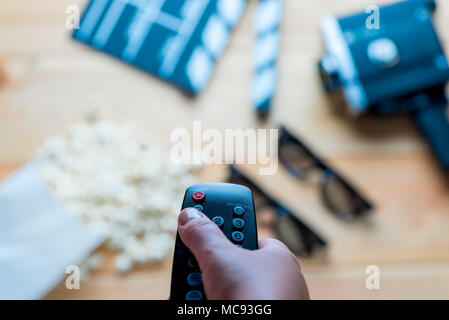 close-up remote control from the TV in hand on the background of movie objects Stock Photo