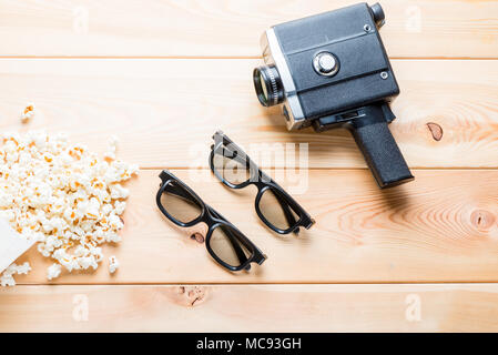 salted popcorn, 3d glasses for two spectators and retro camera on wooden boards top view Stock Photo