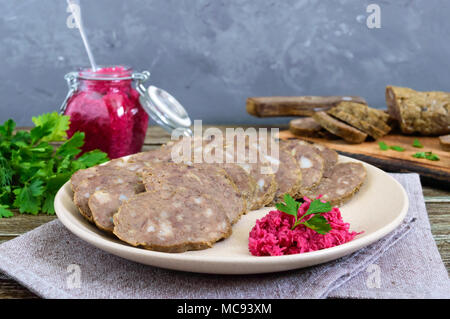 Home made dietary sausage from the liver on a wooden table. Sausage cut into pieces on a plate with horseradish sauce. Stock Photo