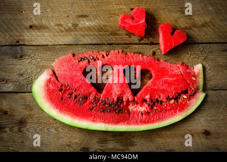 Piece of watermelon with heart shape on old wooden background. Copy space. Flat lay. Greeting card, love concept. Valentine's Day. Stock Photo