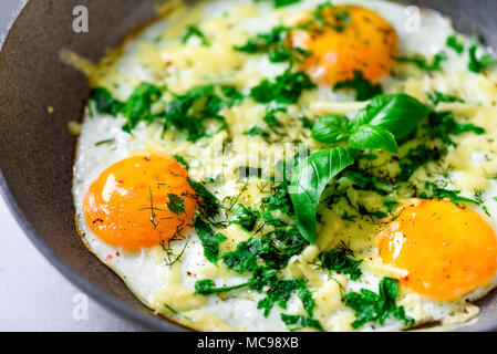 Three fried eggs with peppers, herbs, cheese in pan, closeup, macro Stock Photo