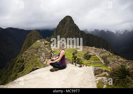 Young woman meditating above Machu Picchu Inca citadel in Peru Stock Photo