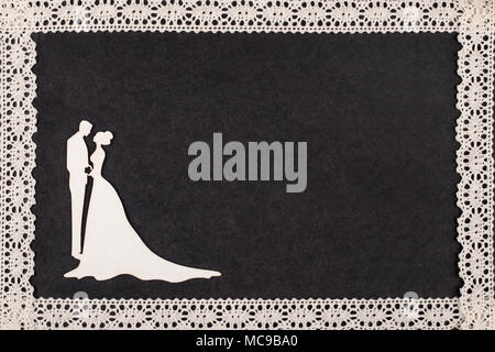 Bride and groom silhouette on retro album page framed with lace. Stock Photo