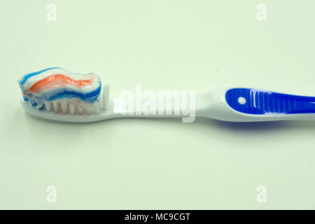 Toothpaste squeezed on the toothbrush on blue background Stock Photo