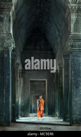 Siem Reap, Cambodia - January 19, 2011: A monk in his orange robe walking inside the Angkor Wat complex. Stock Photo