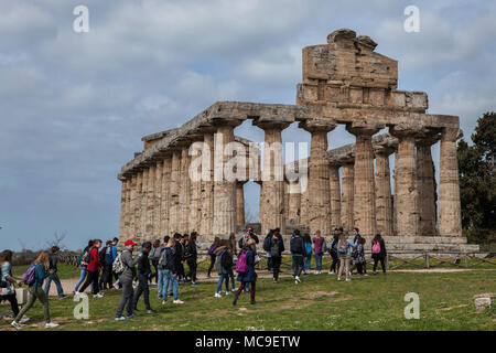 Group of young visitors in front of the Temple of Athena in Paestum, Campania, Italy. The Doric temple dedicated to Athena was built around 500 BC in the Ancient Greek colony of Poseidonia in Magna Graecia and was once incorrectly thought to be dedicated to Ceres. Stock Photo