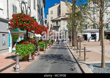 Narrow street decorated with flowers and plants in Old Town of Antibes - Mediterranean resort on Cote d'Azur in France. Stock Photo