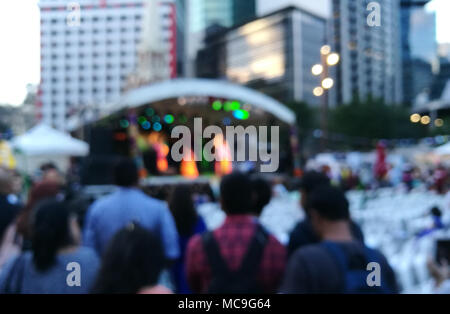 Defocused scene of crowd of people attending public concert celebrating New Year festival in city in Evening Stock Photo