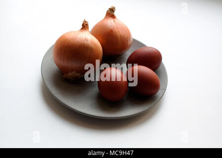 Ripe onions and brown colored eggs on grey concrete plate isolated on white background Stock Photo