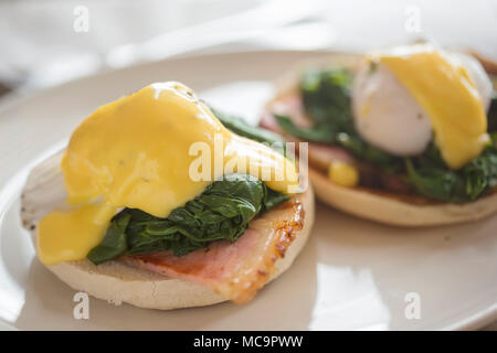 Eggs Benedict. Poached egg on muffin with ham, baby spinach & Hollandaise Stock Photo
